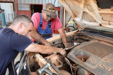 Two men working on a vehicle engine in Zambia.